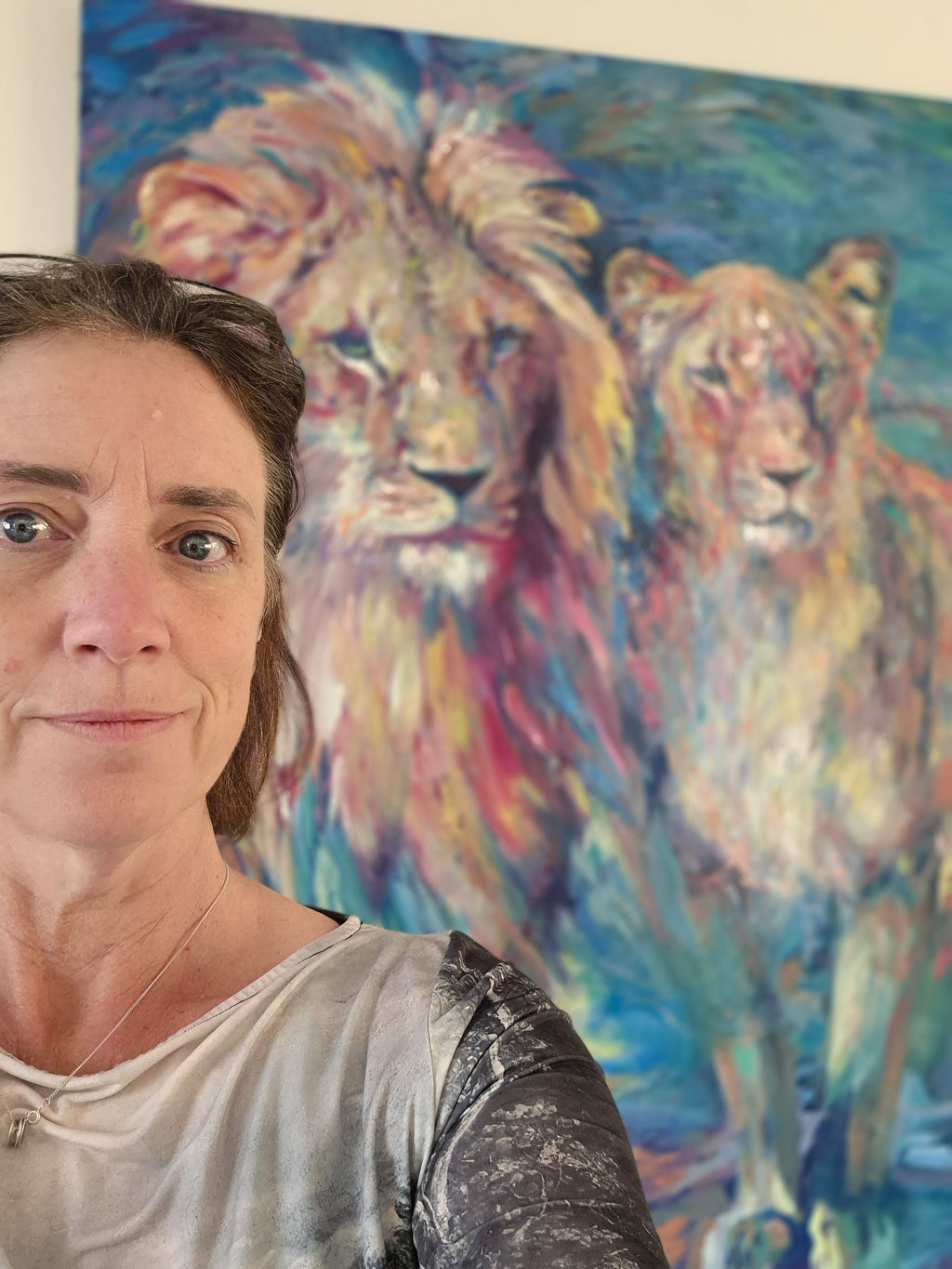 Person standing in front of a colorful painting of two animals.