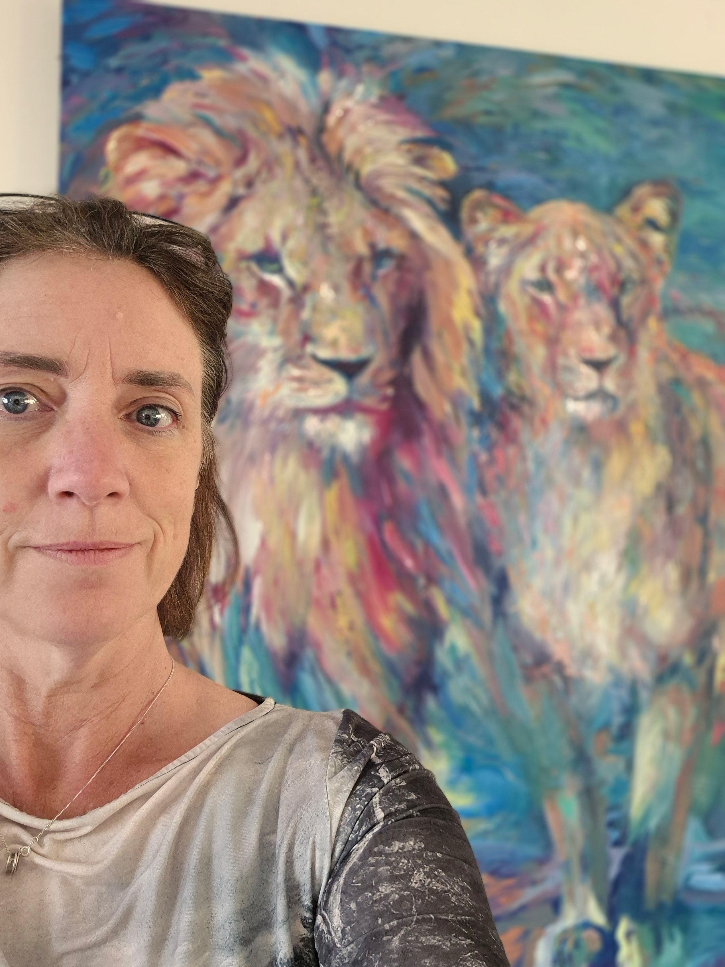 Person standing in front of a colorful painting of two animals.