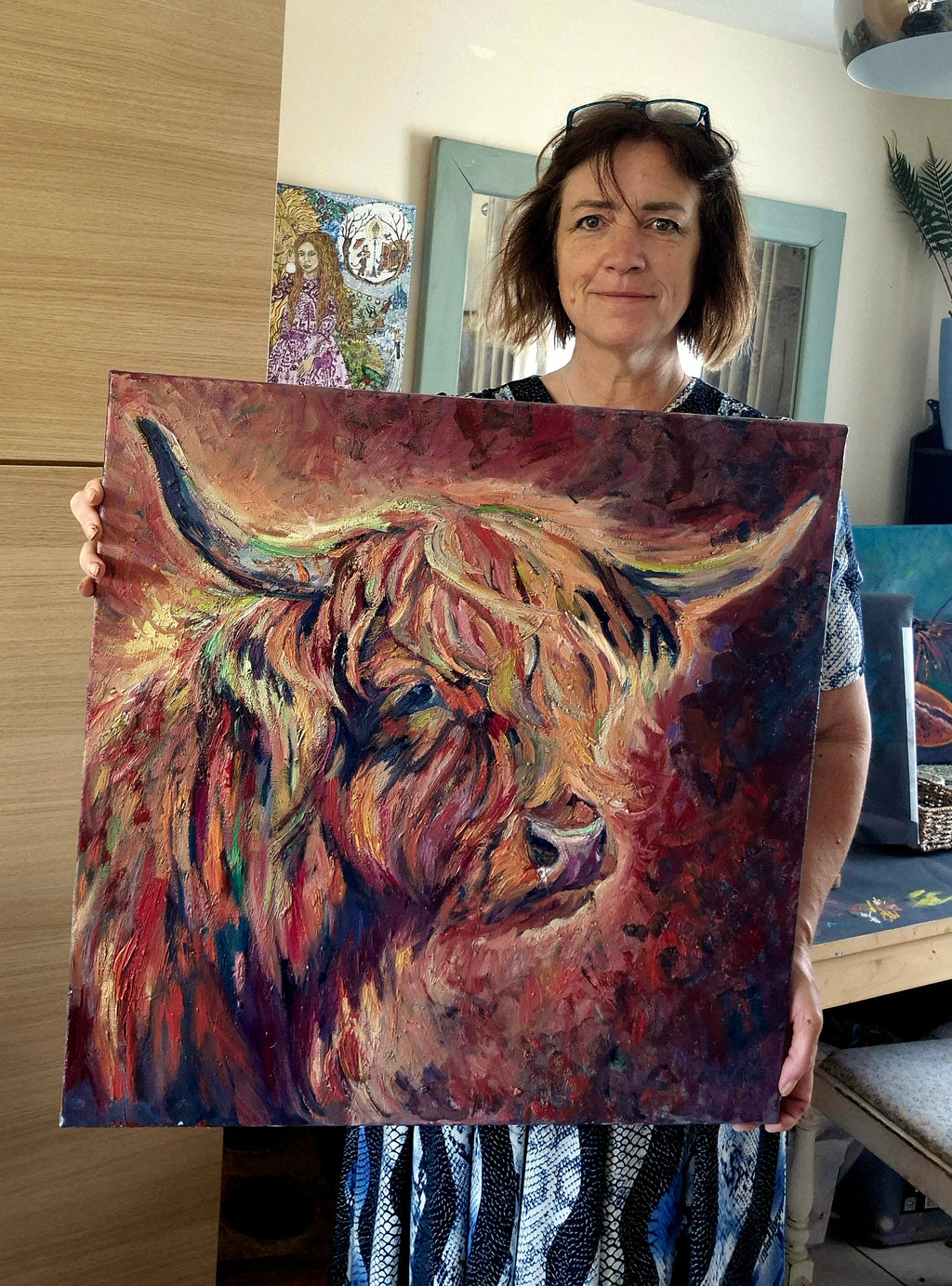 Woman holding a painting of a colorful cow