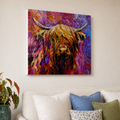A colorful canvas wall art print depicting a Highland cow in an expressive, textured painting, displayed on a beige wall above a modern sofa with decorative pillows and a potted plant.