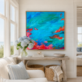 Colorful abstract painting on a wall above a wooden console table with decor items in a living room.