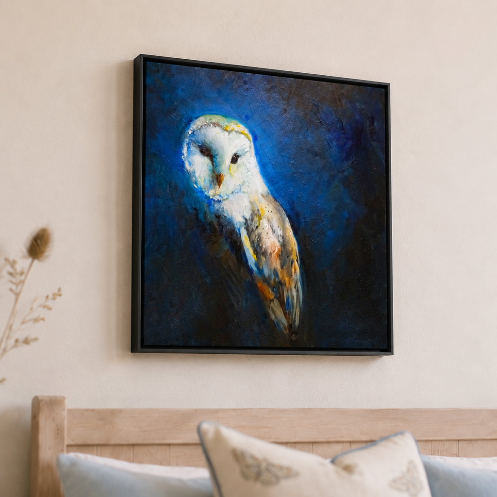 A framed square canvas painting of a barn owl in profile, rendered in deep blue, black, white, and warm brown tones, hanging on a beige wall above a wooden headboard with pillows.