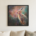 A framed square canvas print of an expressive, colorful painted hare hanging on a light beige wall above a sofa with neutral-toned cushions.