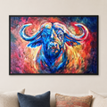 A framed colorful painting of a buffalo hanging on a beige wall above a sofa with cream, navy, and patterned pillows.