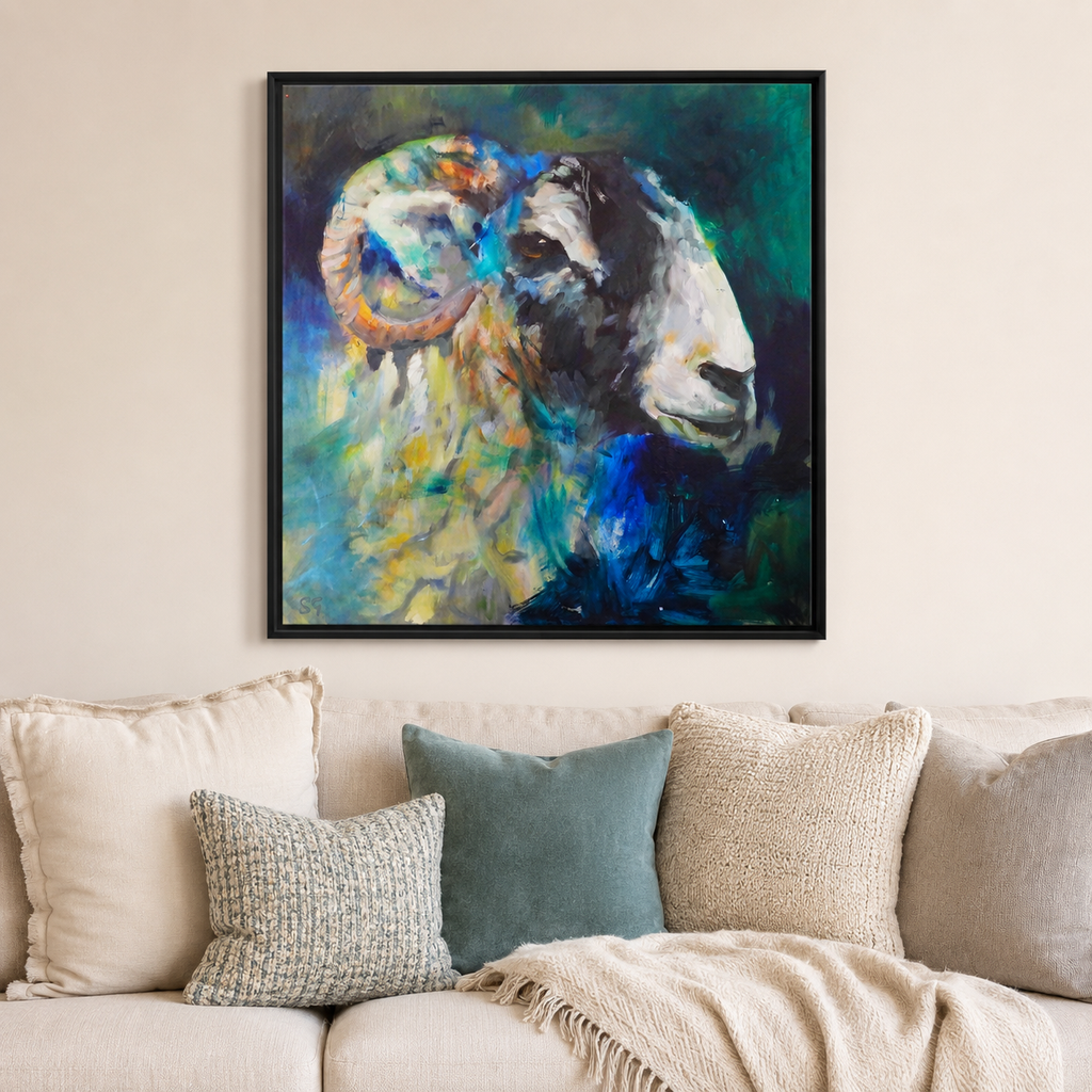 A framed square canvas painting of an abstract ram's head hangs on a beige wall above a couch with neutral-toned pillows and a throw blanket.