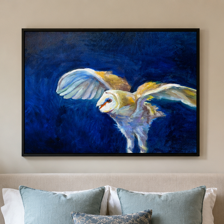 A framed painting of a barn owl in flight against a deep blue background, displayed on a beige wall above a bed with blue and white pillows.