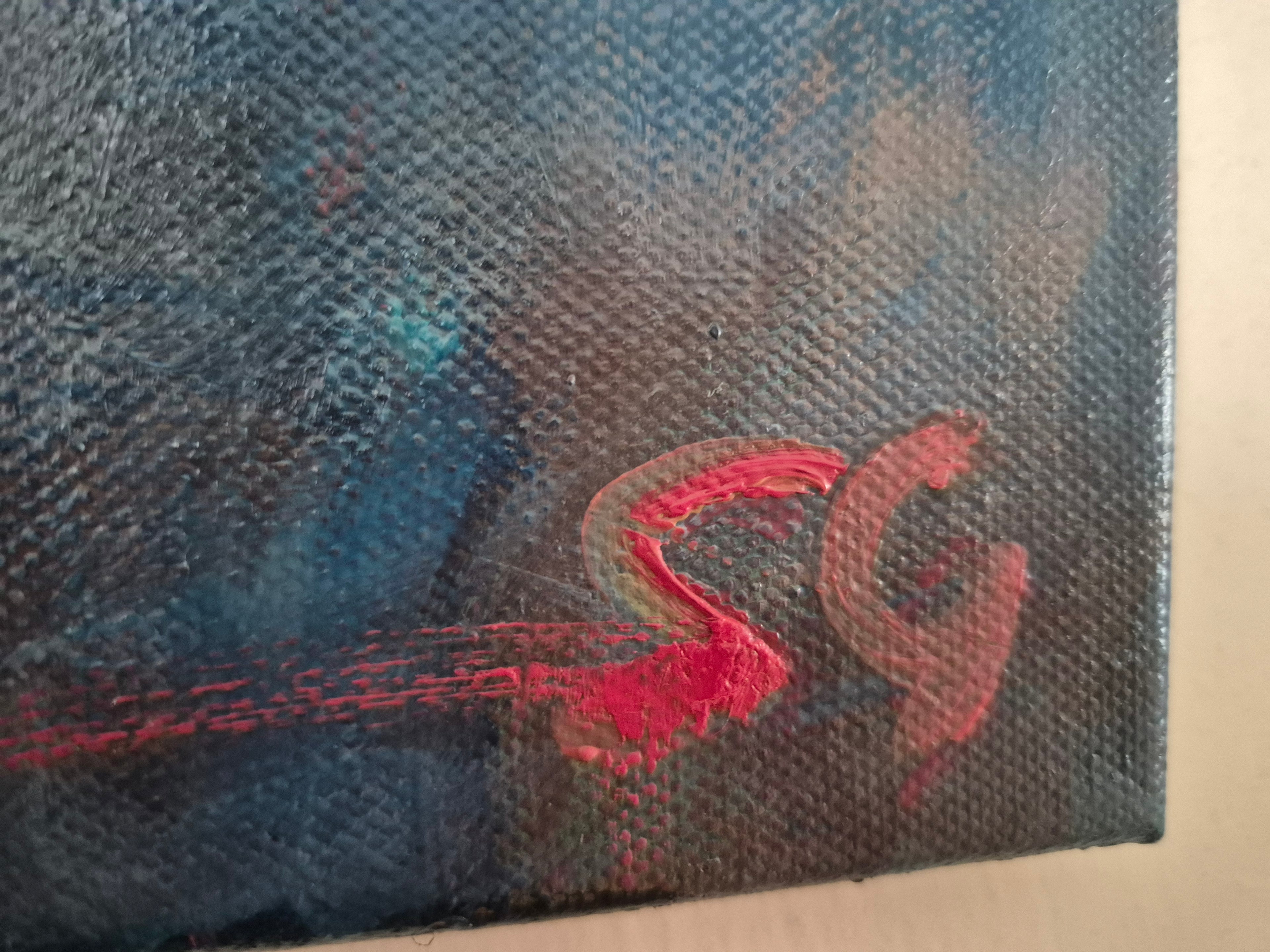 Close-up of a textured surface with a red artists signature on a blue and brown background